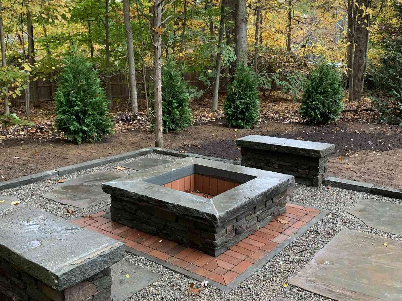 Custom square stone fire pit with bluestone capping and matching stone benches in a Ringwood NJ backyard