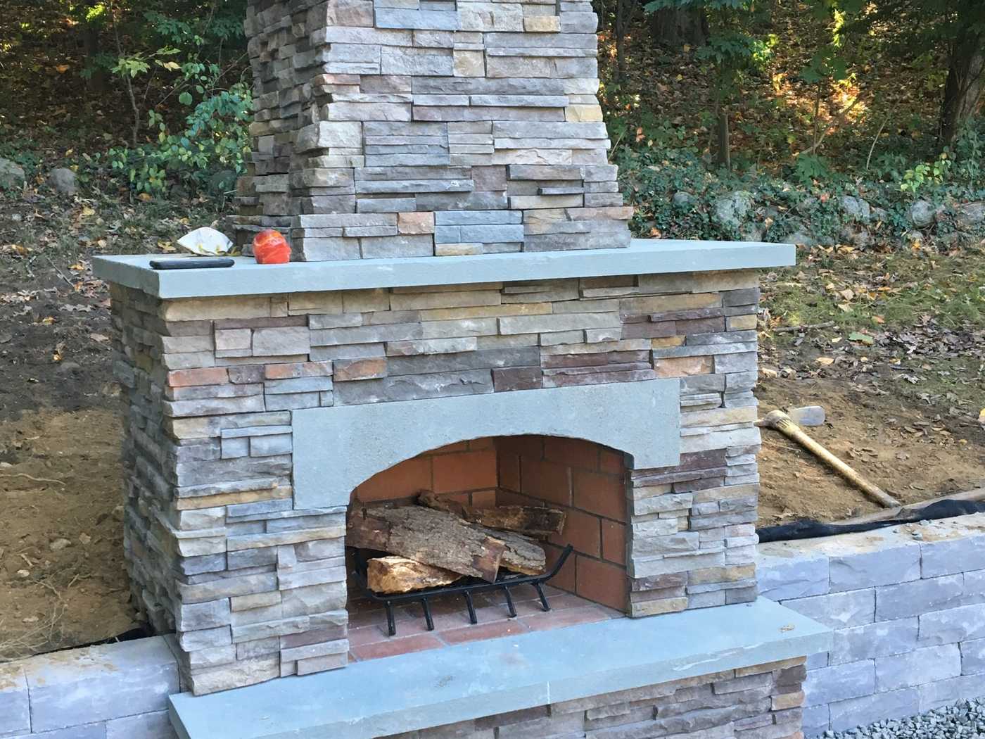 Custom stone veneer outdoor fireplace with bluestone hearth and chimney under construction in Ringwood NJ