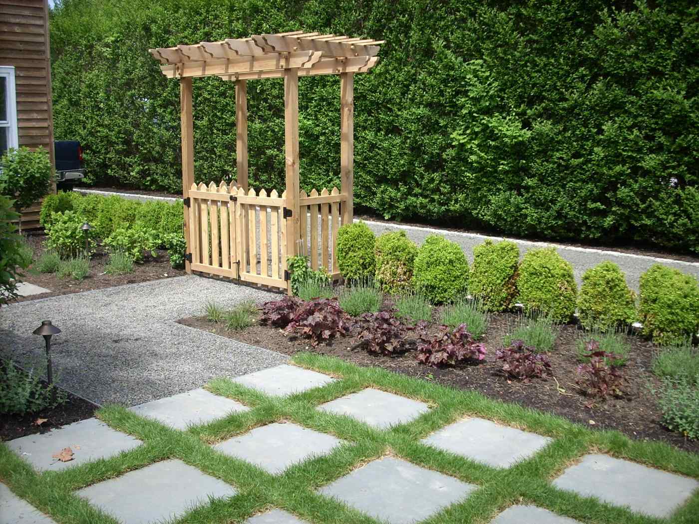 Natural cedar garden arbor with a picket gate integrated into a professional landscape design in Ringwood NJ