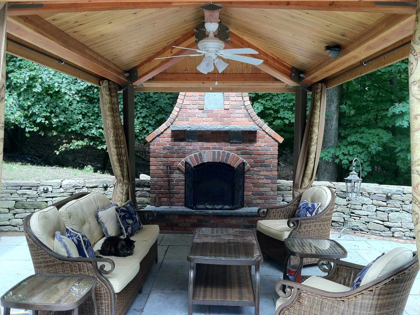 Luxury timber pavilion with a brick outdoor fireplace and stone retaining wall in Ringwood NJ