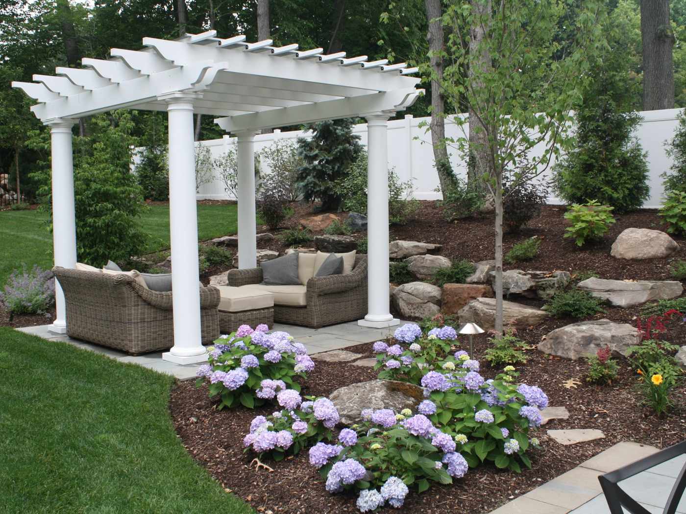 White vinyl pergola with classic columns over a bluestone patio in a Ringwood NJ backyard