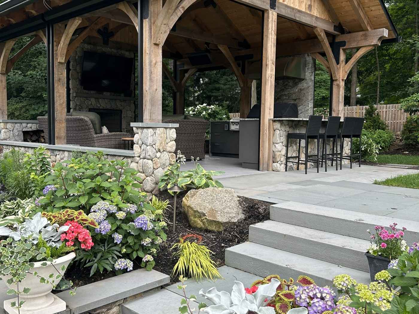 Luxury timber-frame pavilion with stone columns, outdoor kitchen, and bluestone patio in Ringwood NJ