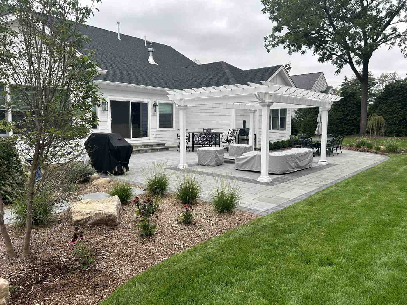 Large white vinyl pergola over a custom paver patio and lounge area in Ringwood NJ