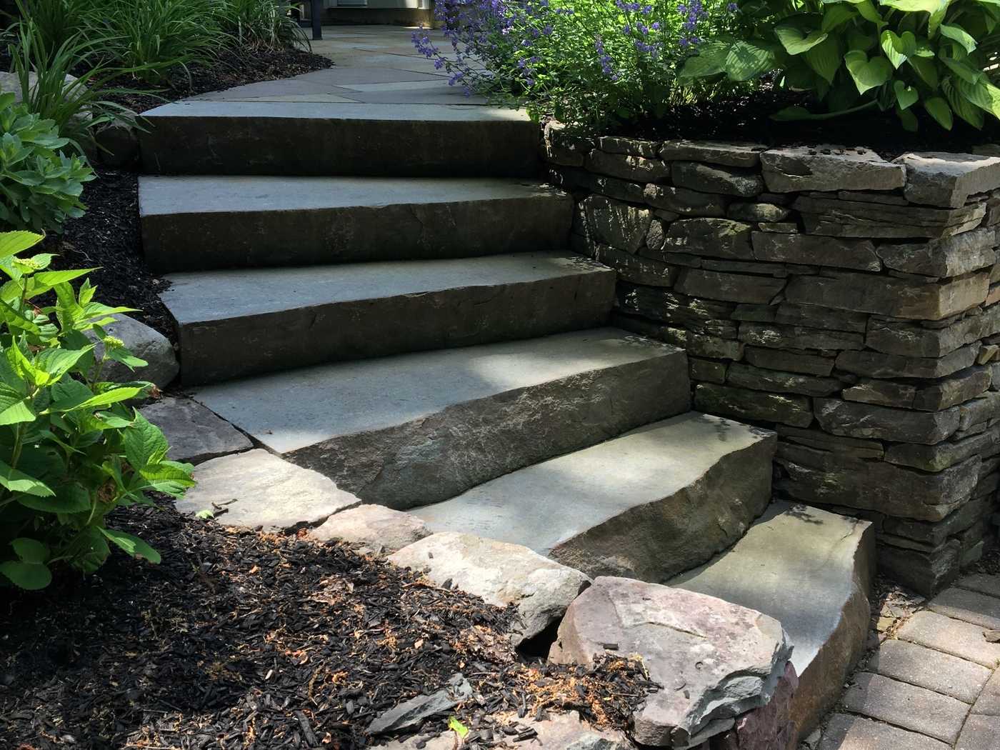 Natural stone slab steps integrated with a dry-stack fieldstone retaining wall in Ringwood NJ