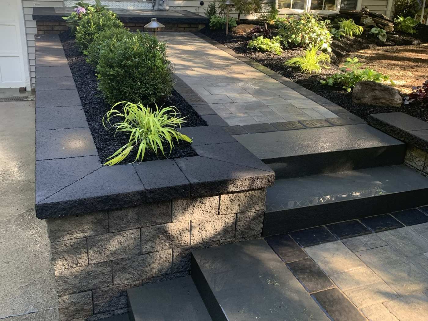 Modern front entry stone walkway with charcoal stone treads and block retaining walls in Passaic County