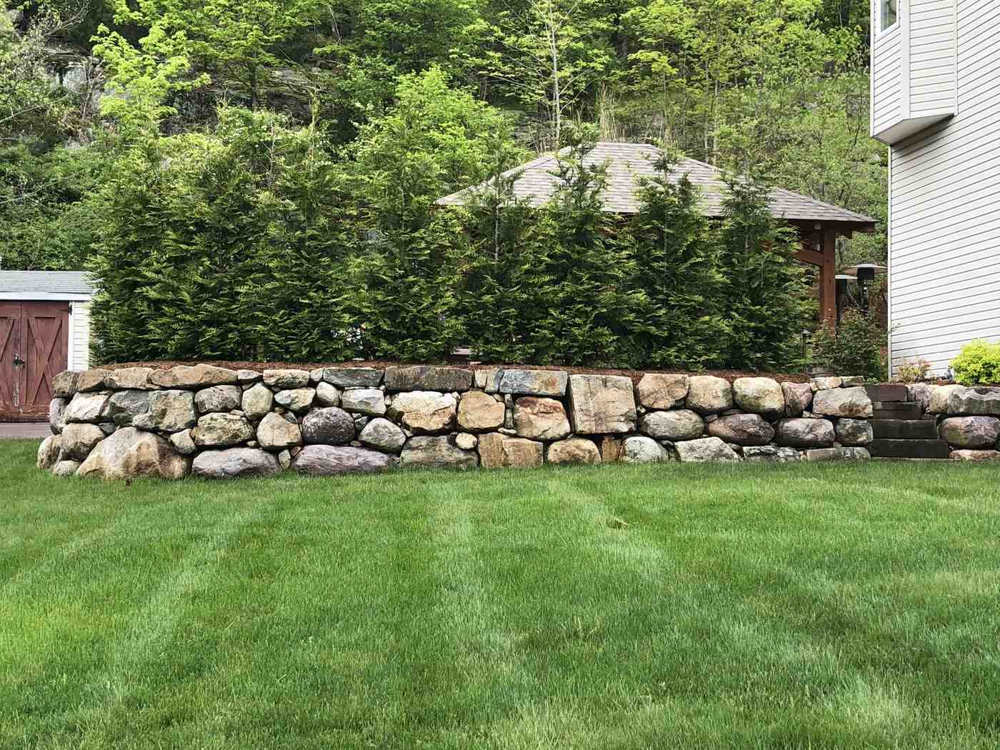 Large natural fieldstone boulder retaining wall installation for erosion control in Ringwood NJ